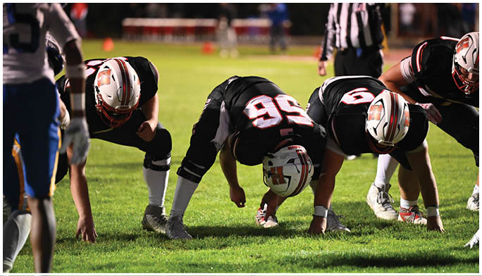 Several people in athletic clothing are crouched on a grass field preparing to start a race or sprint. Description generated by AI