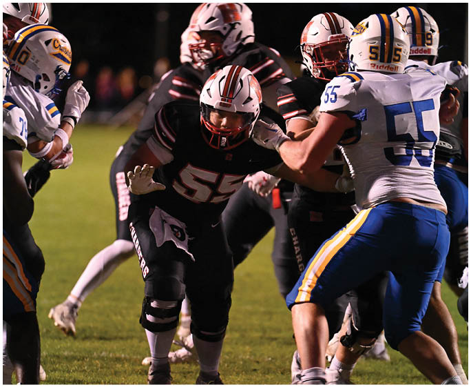 A person wearing a white and red football helmet and black sports gear is engaged in a nighttime outdoor football game. Description generated by AI