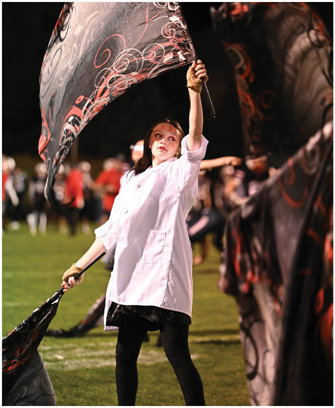 A person is holding a flag with a black background and red and white swirling patterns against a dark night sky. Description generated by AI