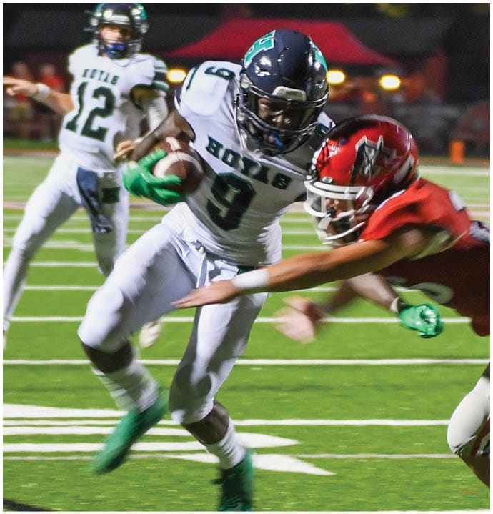 Three football players in blue and white uniforms running on a field. Description generated by AI