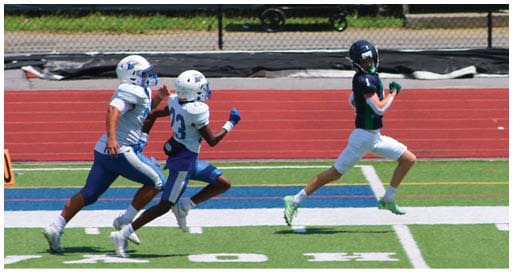 Three football players in blue and white uniforms running on a field. Description generated by AI