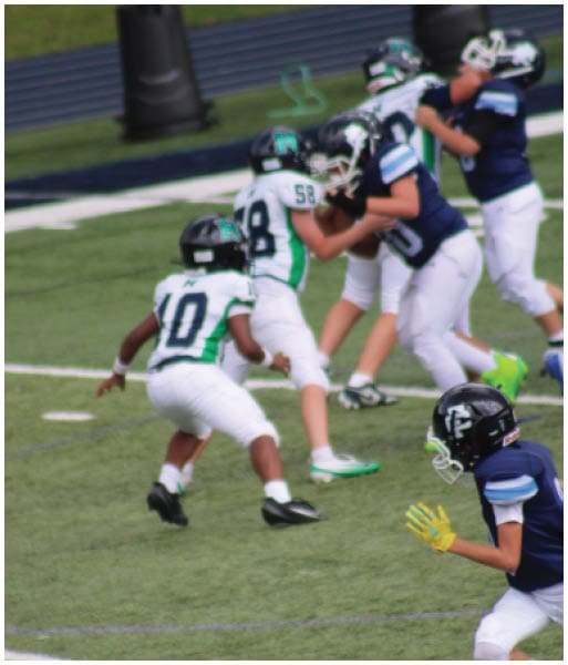 Three football players in blue and white uniforms running on a field. Description generated by AI