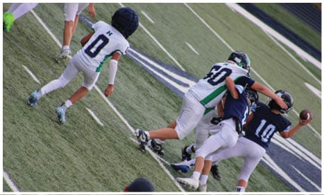 Three football players in blue and white uniforms running on a field. Description generated by AI