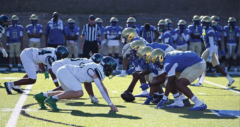 Two men are playing football on a field. One man is tackling the other, who is falling to the ground. AI generated content