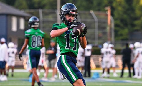 Two men wearing football uniforms are hugging each other on a field. AI generated content