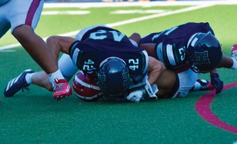 Two men wearing football uniforms are hugging each other on a field. AI generated content