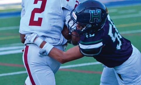 Two men wearing football uniforms are hugging each other on a field. AI generated content