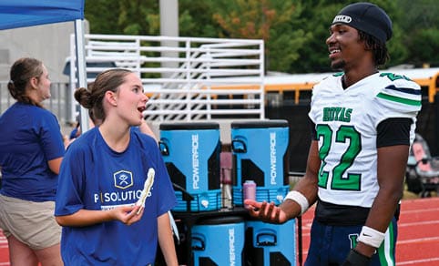 Two men wearing football uniforms are hugging each other on a field. AI generated content