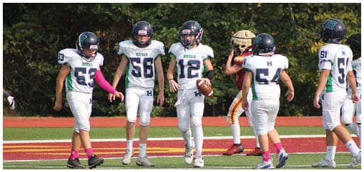 Three football players in blue and white uniforms running on a field. Description generated by AI