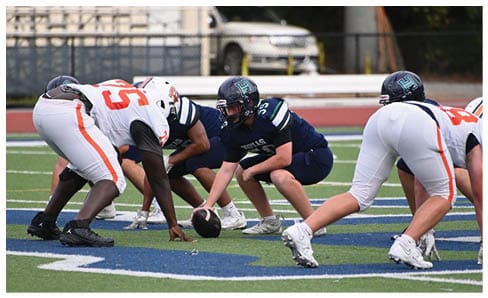 Two men wearing football uniforms are hugging each other on a field. AI generated content