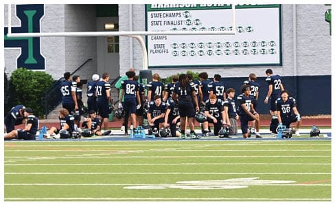 Two men wearing football uniforms are hugging each other on a field. AI generated content