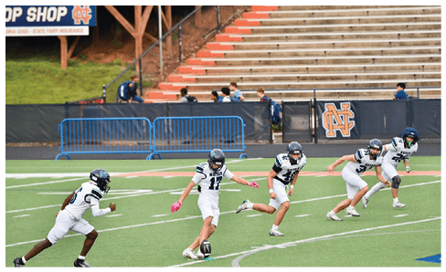 Two men wearing football uniforms are hugging each other on a field. AI generated content