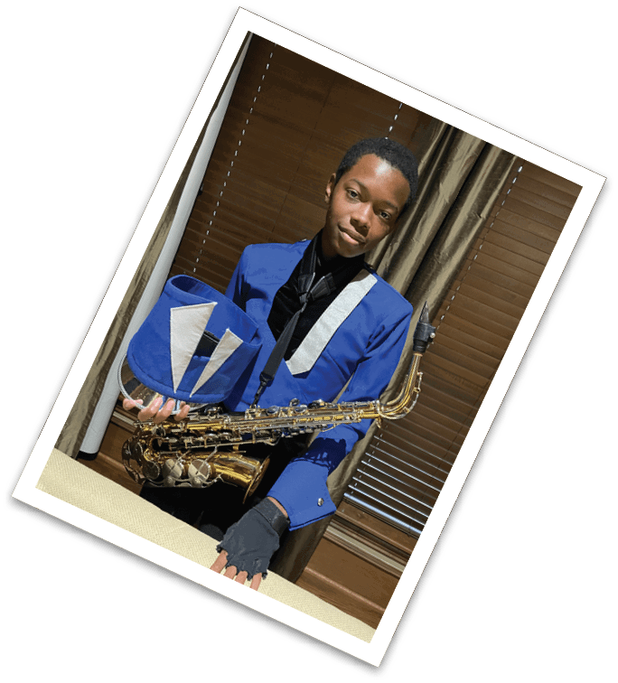 A person wearing a blue and black band uniform is holding a saxophone while sitting indoors in front of brown curtains. Description generated by AI