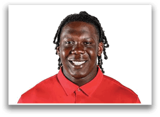 Person with braided hair wearing a red collared shirt smiling against a white background. Description generated by AI