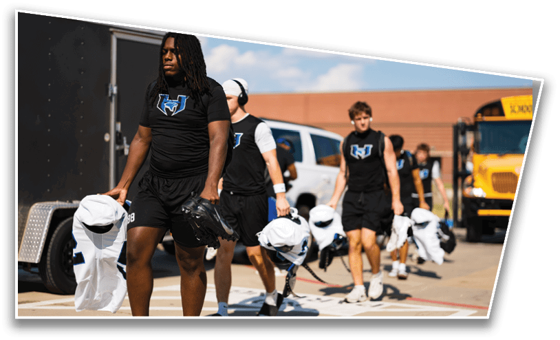 A group of people wearing football helmets and white jerseys with “LA LINDA" written on them are standing closely together on a field. Description generated by AI