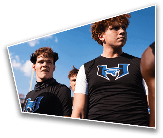A group of people wearing football helmets and white jerseys with “Yorba Linda" written on them stand together outdoors in sunlight. Description generated by AI