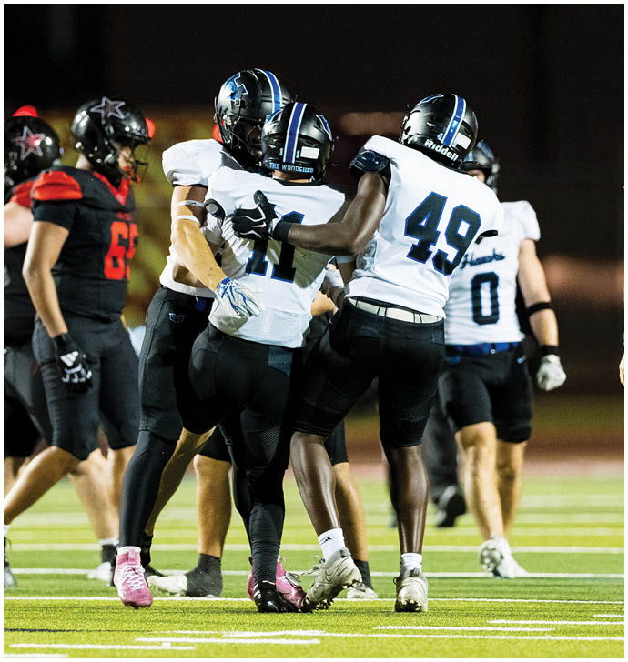 A group of football players wearing black and white uniforms. Description generated by AI
