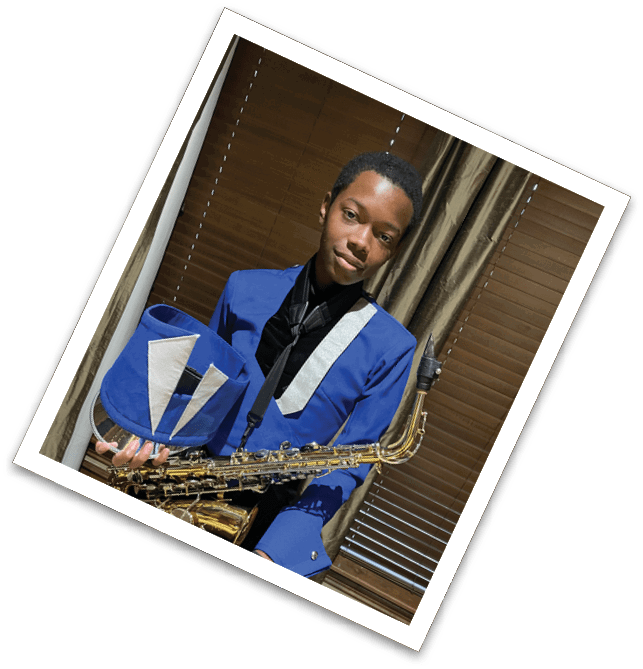 A person wearing a blue and black band uniform is holding a saxophone while sitting indoors in front of brown curtains. Description generated by AI