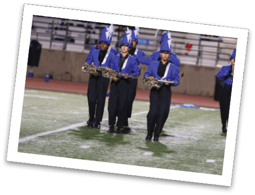People in blue and black marching band uniforms with tall blue hats are playing saxophones while marching on a field. Description generated by AI