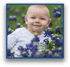 A person wearing a white long-sleeve shirt is lying or sitting among a field of purple flowers with green foliage. Description generated by AI