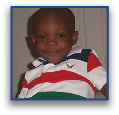 A child wearing a colorful striped polo shirt is smiling while sitting indoors. Description generated by AI