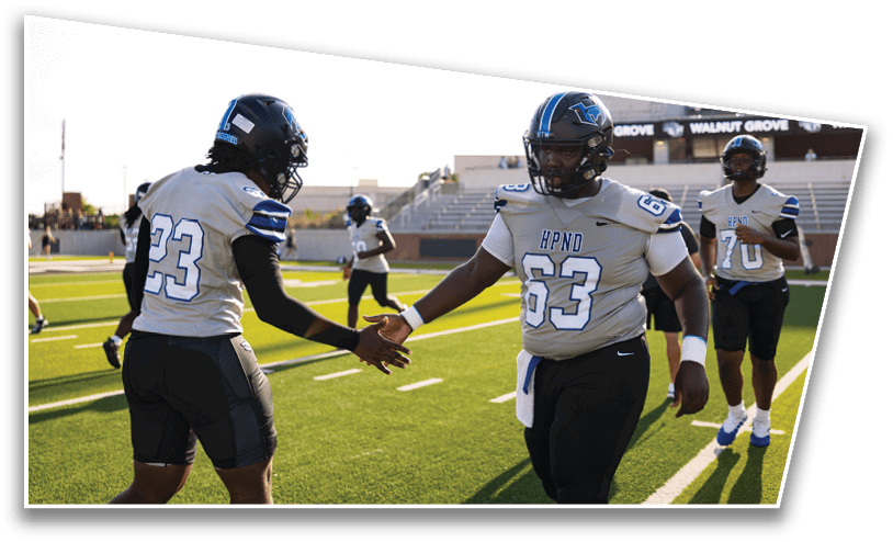 Two people in football uniforms are giving each other a handshake on a football field while two others stand nearby. Description generated by AI