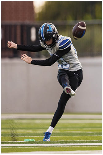 A person wearing a football helmet and uniform is extending their arms forward, appearing to be in motion during a game. Description generated by AI