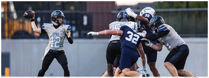 A group of people in football uniforms are engaged in a play on a field with one person preparing to throw a football. Description generated by AI