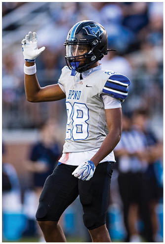 A person wearing a football helmet and white jersey with the number 88 and the letters HPND is raising one gloved hand. Description generated by AI