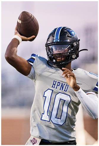 A person wearing a football helmet and a gray jersey with the number 10 is preparing to throw a football. Description generated by AI