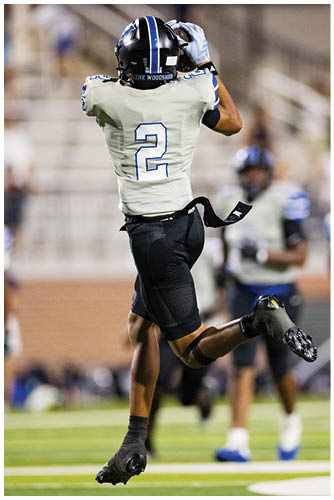 A person wearing a football uniform with the number 2 on the back is preparing to catch or throw a ball on a blurred outdoor field. Description generated by AI