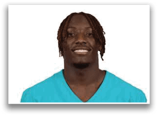 Person with braided hair wearing a teal shirt smiling against a white background. Description generated by AI