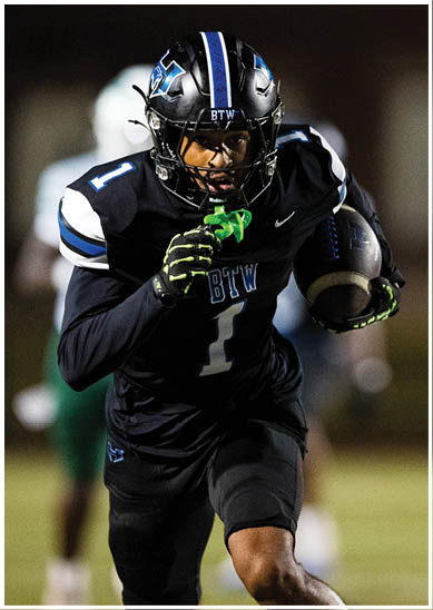 A person wearing a black football uniform with the number one is running on a field while holding a football. Description generated by AI