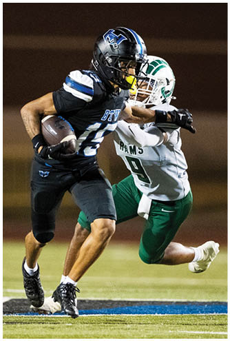 Two people in football uniforms are engaged in a play on a field, with one person holding the ball and the other attempting to tackle. Description generated by AI