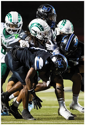 Several people in football uniforms are engaged in a close, intense play on a grassy field during a game. Description generated by AI