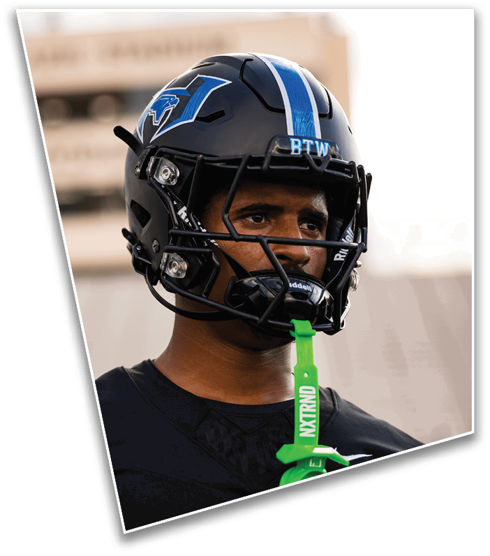 A person wearing a black football helmet with blue and white stripes and the letters BTW on the front is looking ahead. Description generated by AI