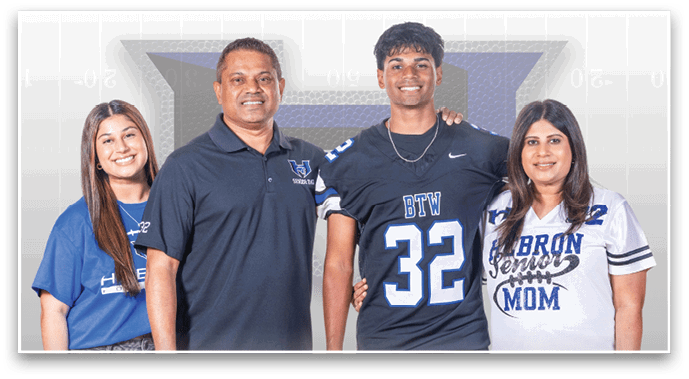 Four people standing closely together smiling with one person wearing a sports jersey and another wearing a shirt that says “Senior Mom." Description generated by AI