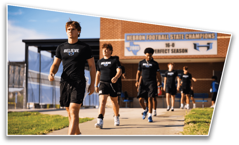 A group of people wearing matching black athletic clothing with the word “BELIEVE" walk on a sidewalk outside a building with a sign celebrating a perfect football season. Description generated by AI