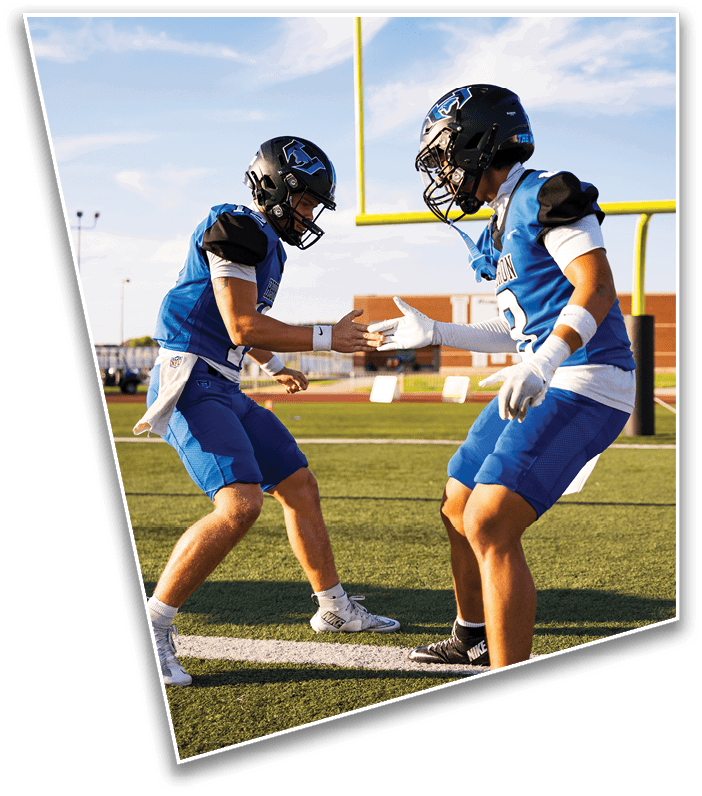 Two people wearing athletic clothing and cleats are standing on a sports field near a white line, appearing to be engaged in a physical activity or game. Description generated by AI
