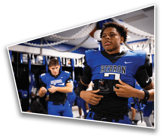 People in blue football uniforms are preparing and adjusting their gear in a decorated locker room. Description generated by AI