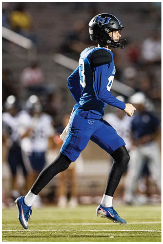 A person in a blue football uniform and helmet is running on a field during a game. Description generated by AI