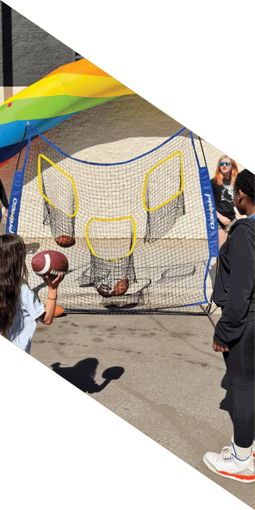Two football players are on the field, one jumping in the air while the other is running. A referee is also present, watching the play. AI generated content