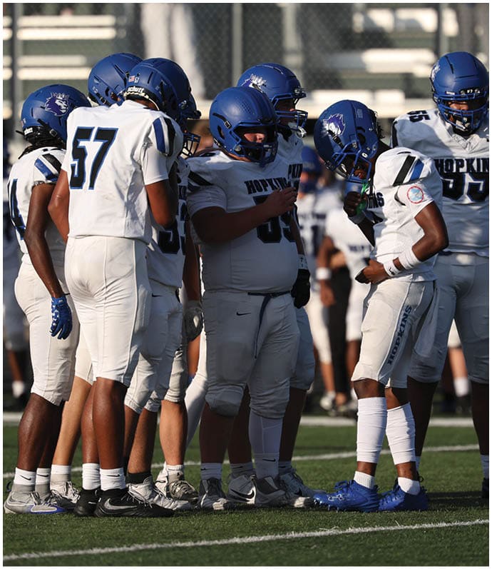 A group of football players wearing black and white uniforms. Description generated by AI
