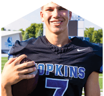 A young man wearing a white jersey with the number 10 on it. Description generated by AI