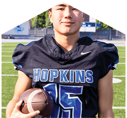 A young man wearing a white jersey with the number 10 on it. Description generated by AI
