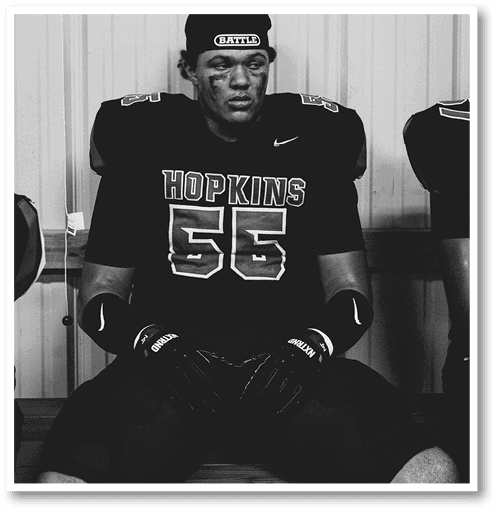 A football player wearing a black jersey with the number 6 on it. Description generated by AI