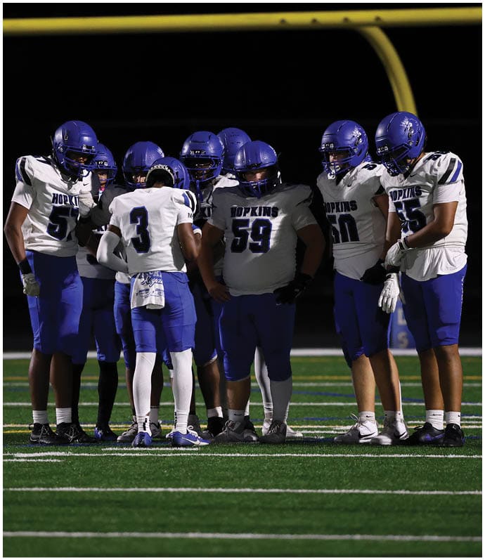 A group of football players wearing black and white uniforms. Description generated by AI