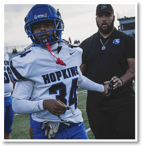 A football player wearing a black jersey with the number 6 on it. Description generated by AI