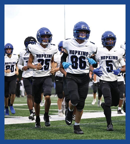 A football player in a white uniform is running with a football in his hand. AI generated content