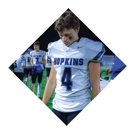 A football player wearing a black jersey with the number 3 kneels on the field. AI generated content